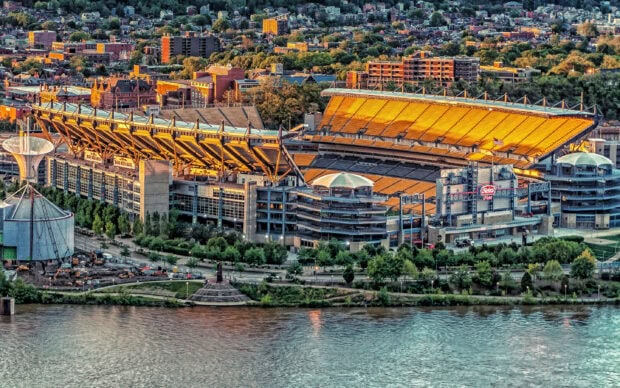 Heinz Field stadium in Pittsburgh cityscape during sunset with river in foreground