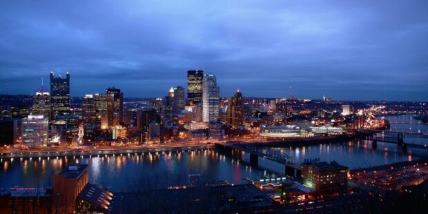 Night view of Pittsburgh city skyline reflecting on the river with illuminated buildings and bridges