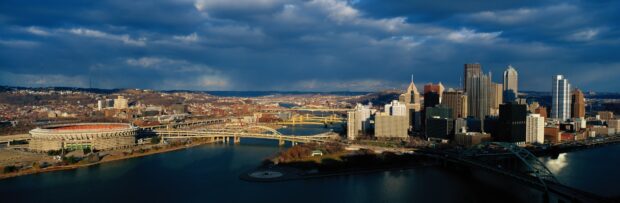 Pittsburgh city skyline and bridges over the river with stadium and hills in clear daylight