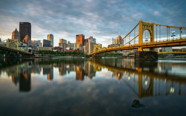 Pittsburgh skyline with golden bridge and river reflection at sunset
