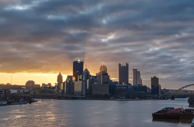 Pittsburgh city skyline at sunset with dramatic clouds and river view