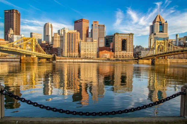 Pittsburgh city skyline with its yellow bridges and reflections on the water at sunset