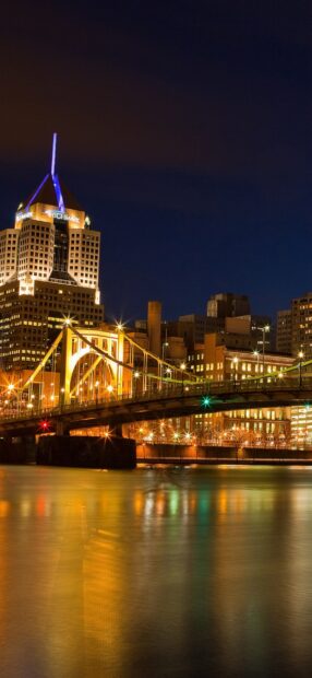 Illuminated Pittsburgh skyline at night with bridge and Highmark building reflections