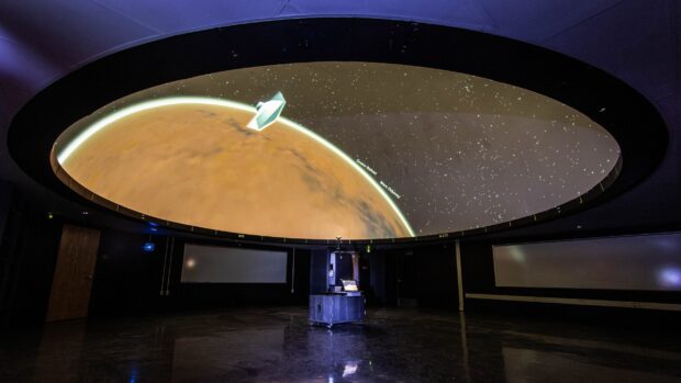 A detailed planetarium dome showing a glowing planet and star map in a dark room
