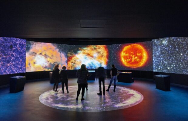 People observing vibrant astronomical displays in a planetarium exhibition