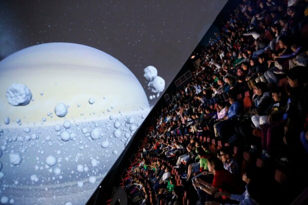 People watching a planetarium showing celestial objects and planetary features in 2K quality