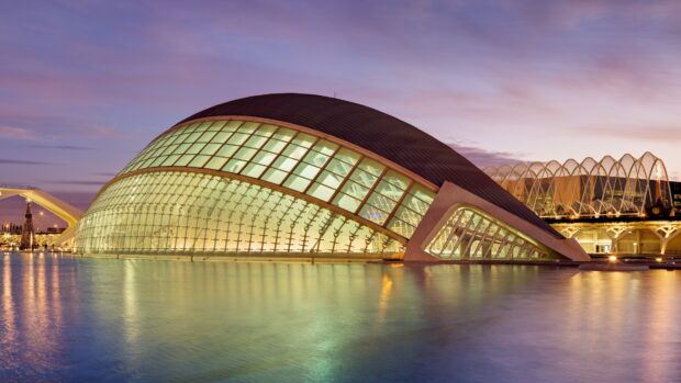 A modern architectural structure of the planetarium surrounded by water at sunset with a colorful sky