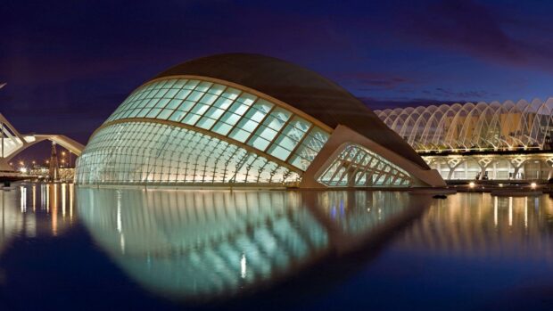 Modern planetarium building illuminated at night with reflections in water