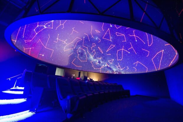 A planetarium displaying constellations and the Milky Way galaxy in a dark theater setting