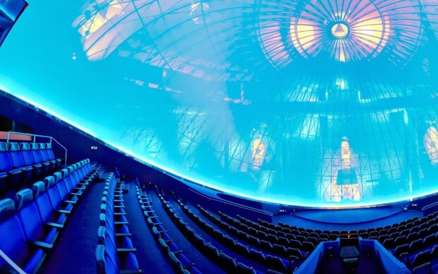 Interior view of a planetarium dome with blue seating and star projection system