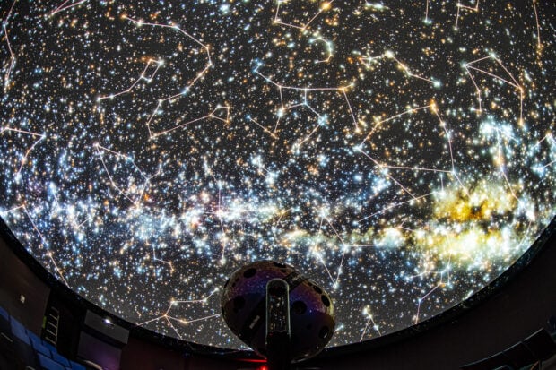 A planetarium dome displaying detailed stars and constellations in a vibrant night sky