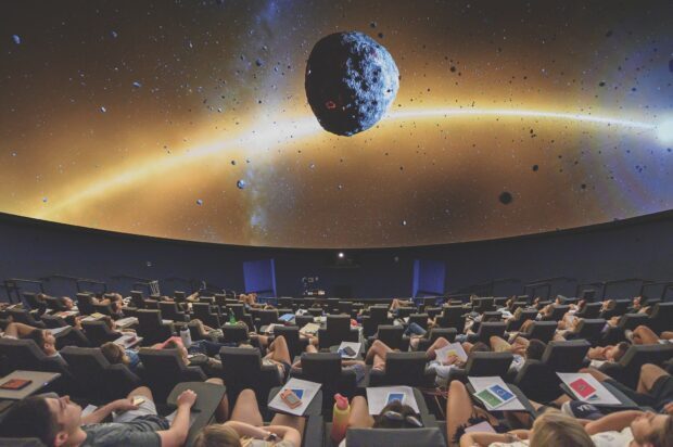 Students watching a planetarium projection showing an asteroid and space elements