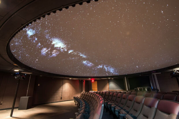 The planetarium projection showing stars and galaxies on the dome ceiling of a theater room
