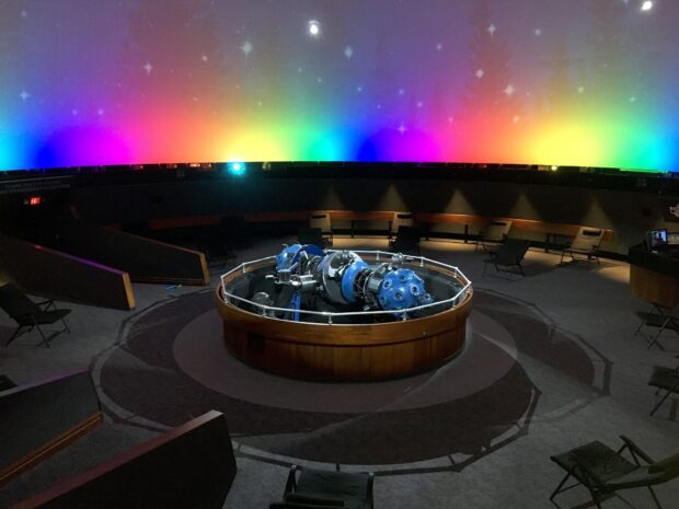 A planetarium device with colorful lights displaying stars in a dark dome interior