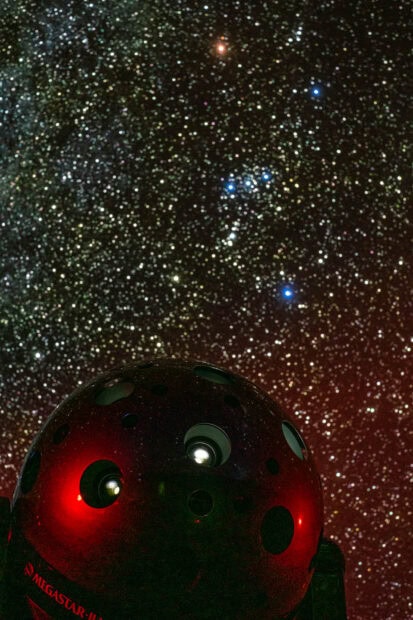 A planetarium device projecting stars under a clear night sky filled with countless stars