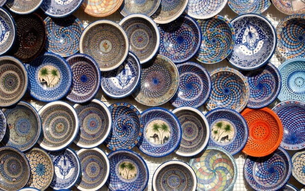 A collection of decorative ceramic plate designs with intricate patterns and colors displayed on a wall