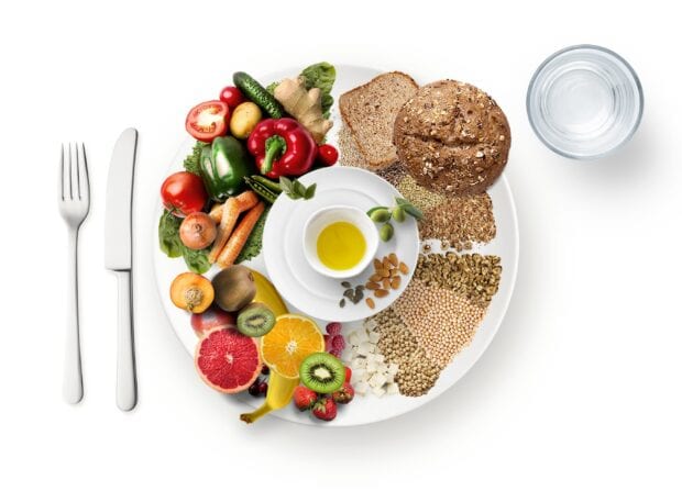 A healthy plate containing vegetables grains and fruits arranged neatly for a balanced meal