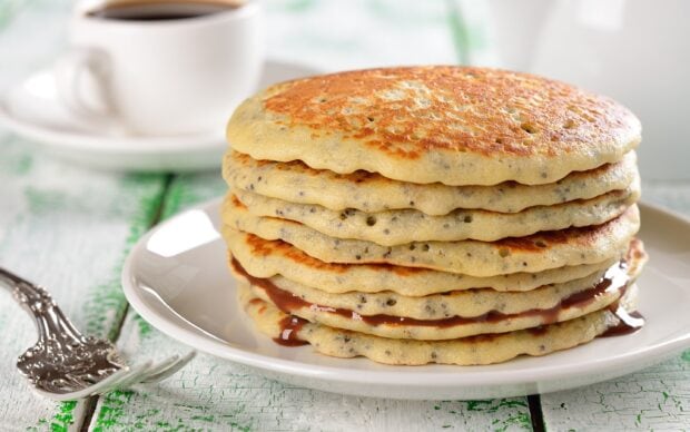 A stack of fluffy chia seed pancakes with chocolate spread on a white plate