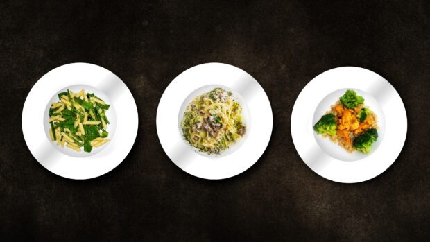 Three plates with pasta dishes arranged on a dark textured surface featuring healthy meal options