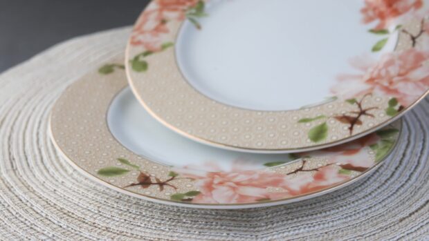 Two decorative plates with floral patterns on a textured placemat showing plate details