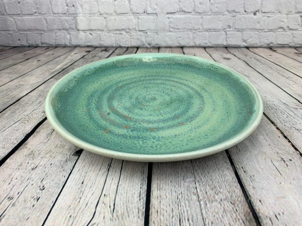A green ceramic plate with a textured pattern on a wooden surface