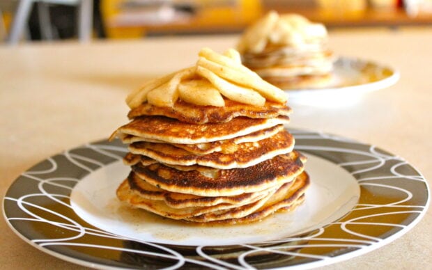 A stack of pancakes with sliced banana on a decorative plate