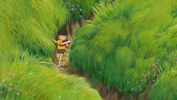 A boy carrying a toy boat walking through green grass in Ponyo