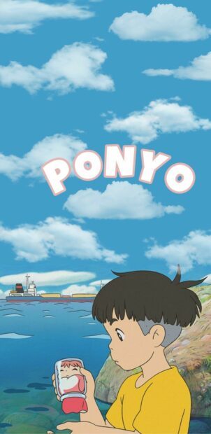 A boy in a yellow shirt holding a small Ponyo figure near the ocean shore