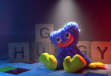 Huggy is sitting with colorful wooden blocks in a dark room