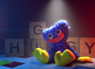 Huggy is sitting with colorful wooden blocks in a dark room