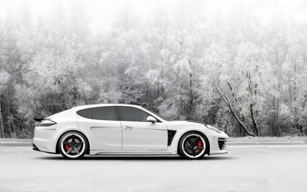 A white Porsche Panamera parked on a snowy road with frost covered trees in the background