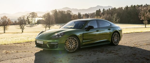 Green Porsche Panamera parked on a road with trees and mountains in the background