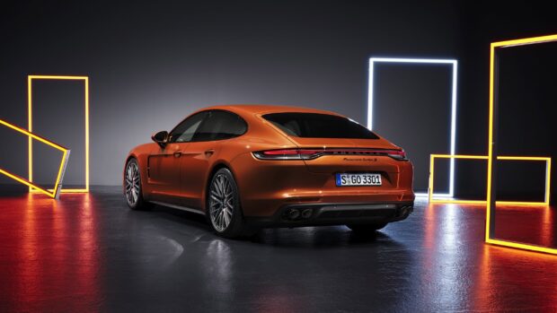 Orange Porsche Panamera car parked in a studio with neon light frames around