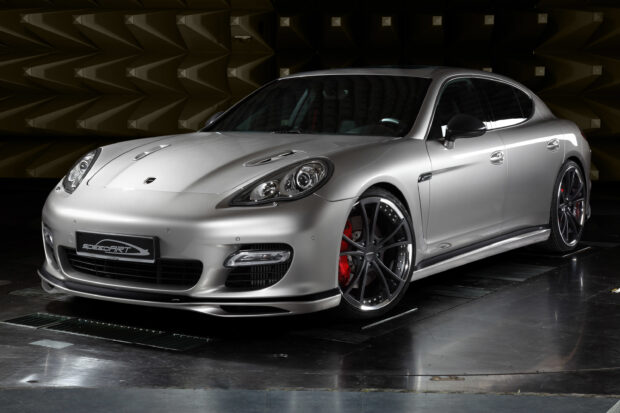 Silver Porsche Panamera with black rims and red brake calipers parked in a dark studio