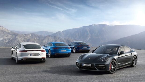 A group of Porsche Panamera cars parked on a mountain road with scenic mountain background