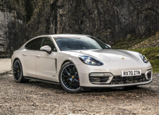 White Porsche Panamera GTS parked on a mountain road with rocky cliffs in the background