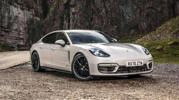 White Porsche Panamera GTS parked on a mountain road with rocky cliffs in the background