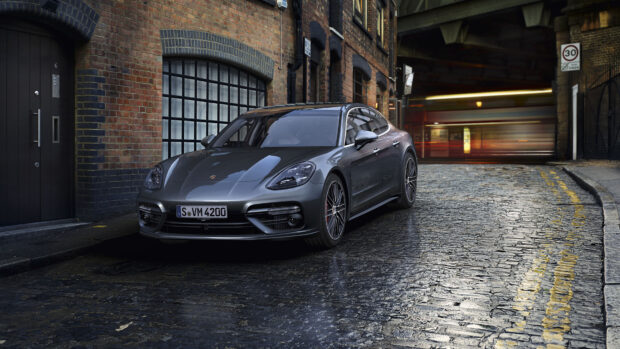 A grey Porsche Panamera parked on a cobblestone street in an urban setting