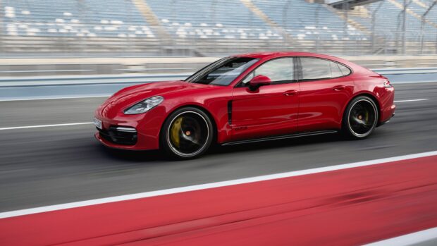 Red Porsche Panamera driving fast on a racetrack with blurred background