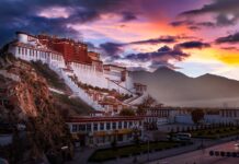 The majestic Potala Palace surrounded by mountains under a colorful sunset sky
