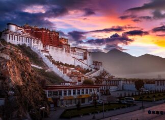 The majestic Potala Palace surrounded by mountains under a colorful sunset sky