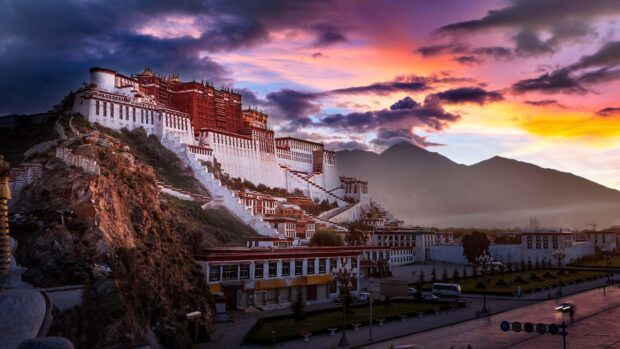 The majestic Potala Palace surrounded by mountains under a colorful sunset sky