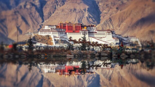 The Potala Palace reflected in still water with surrounding mountains and festive decorations