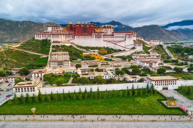 Potala Palace is a historic palace with intricate architecture set against a mountain backdrop in vibrant colors