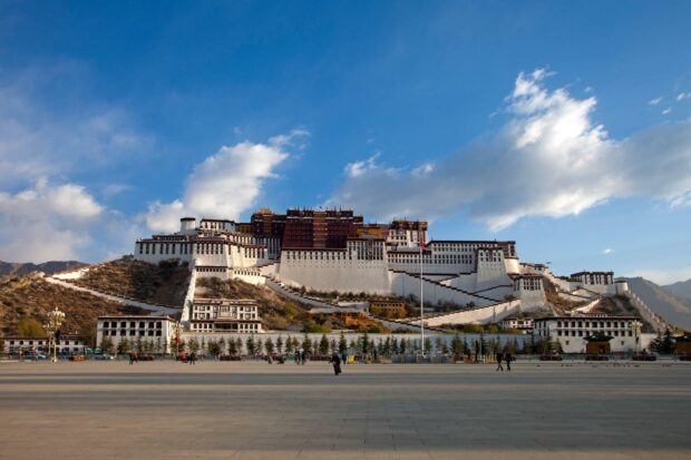 The famous Potala Palace stands prominently against a clear blue sky