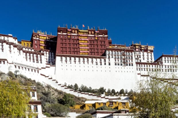 The historic Potala Palace stands majestically against a clear blue sky in Tibet