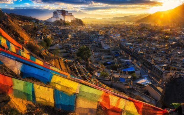 Colorful prayer flags fluttering near Potala Palace at sunset in Tibet with city view