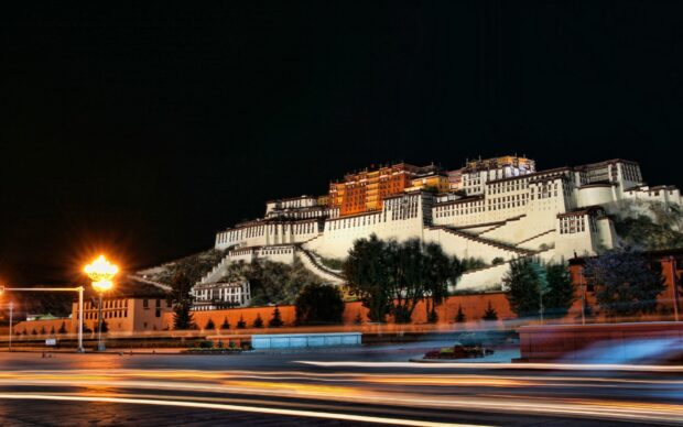 Potala Palace illuminated at night with light trails in front of the historic building
