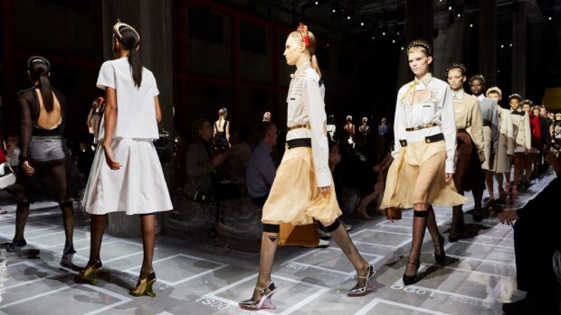 Models walking on runway at a Prada fashion show with elegant clothing and accessories