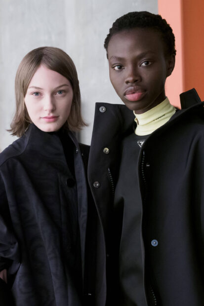 Two models wearing stylish Prada outfits posing together in a high fashion setting